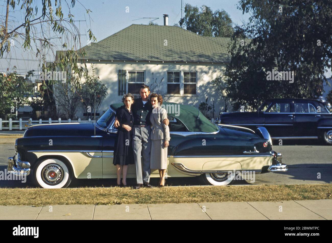 Ein Mann zeigt seinen Stolz und seine Freude, ein Pontiac Star Chief Verdeck Auto USA c. 1955. Er hat seine Arme um zwei Frauen, die stilvoll gekleidet sind, eine jüngere und die andere ältere. Zwischen 1954 und 1957 war der Star Chief Pontiacs Prestigemodell und basierte auf dem Pontiac Chieftain. Stockfoto