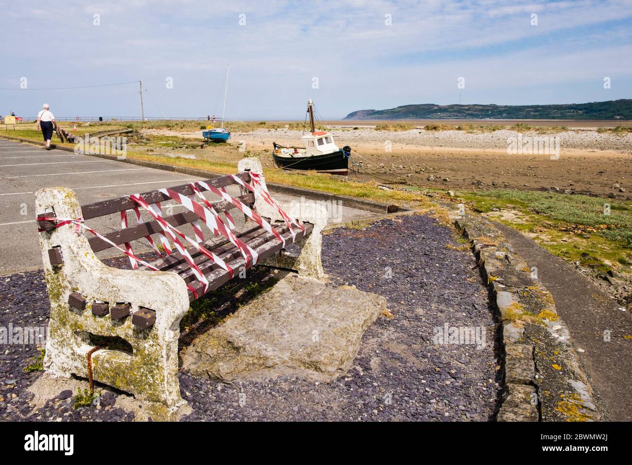 Geschlossene Bank mit rot-weißem Warnband für soziale Distanzierungsregeln während der neuen Covid-19-Sperre im Juni 2020 abgeklebt. Anglesey, Nordwales, Großbritannien Stockfoto