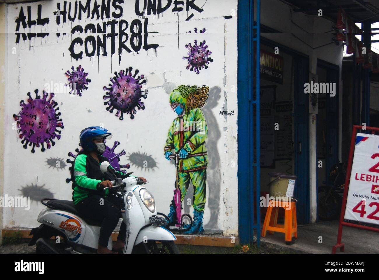 1. Juni 2020, Sleman, YOGYAKARTA, INDONESIEN: Online-Motorradtaxi-Fahrer benutzen Masken, wenn sie das Wandbild mit dem Corona-Virus-Logo in Sleman, Yogyakarta, Indonesien, Dienstag, 1. Juni 2020, passieren. Bis zum 2. Juni 2020 wurden in Indonesien insgesamt 27,549 Fälle von Toten, die 1,663 Menschen erreichten, von Corona-Viren ausgebrochen. (Bild: © Slamet Riyadi/ZUMA Wire) Stockfoto