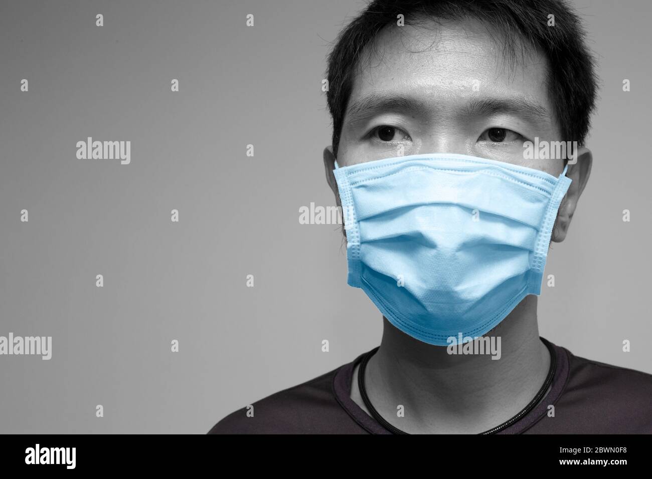 Asiatische chinesische Mann trägt Gesichtsmaske oder Einweg-Schutzschild Tuch Abdeckung Studio Kopf geschossen mit Platz für Text. Stockfoto