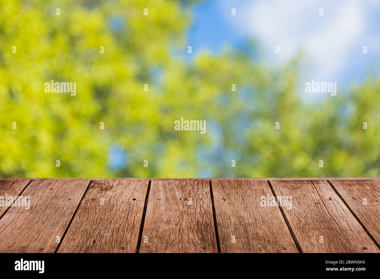 Blur grünen Baum Hintergrund mit Holztisch Vordergrund für Werbung natürliche Produkte Overlay Vorlage. Stockfoto