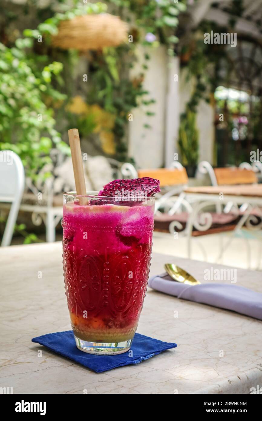 Rosa Saft mit Äpfeln, Rote Bete, Drachenfrucht und Limette im Glas mit Bambus Trinkhalm auf dem Tisch im Café Stockfoto
