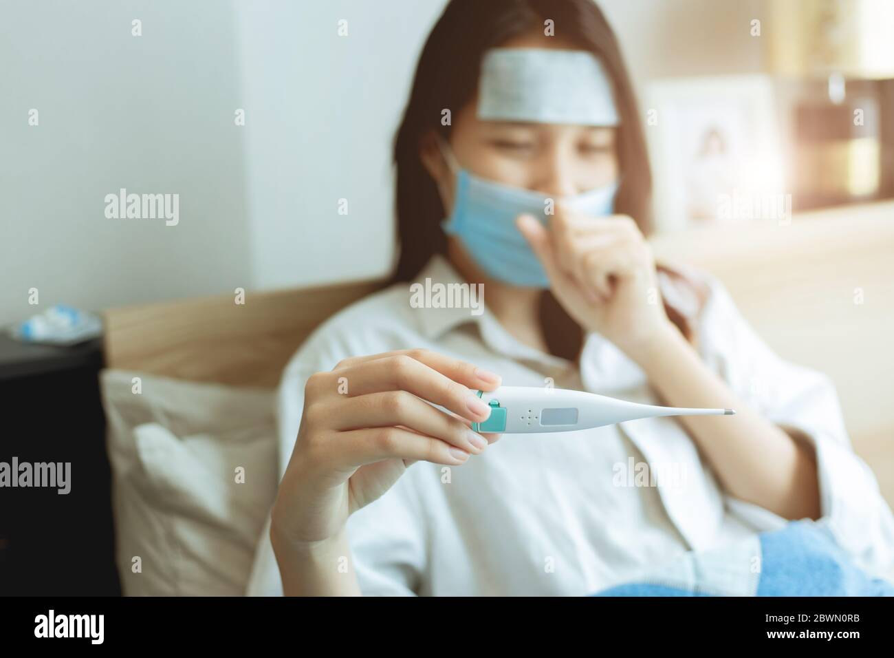 Asiatische Frauen suchen Körpertemperatur auf orale Thermometer für die Diagnose Grippe von Coronavirus (Covid-19) Infektion Selbstversorgung zu Hause bleiben. Stockfoto