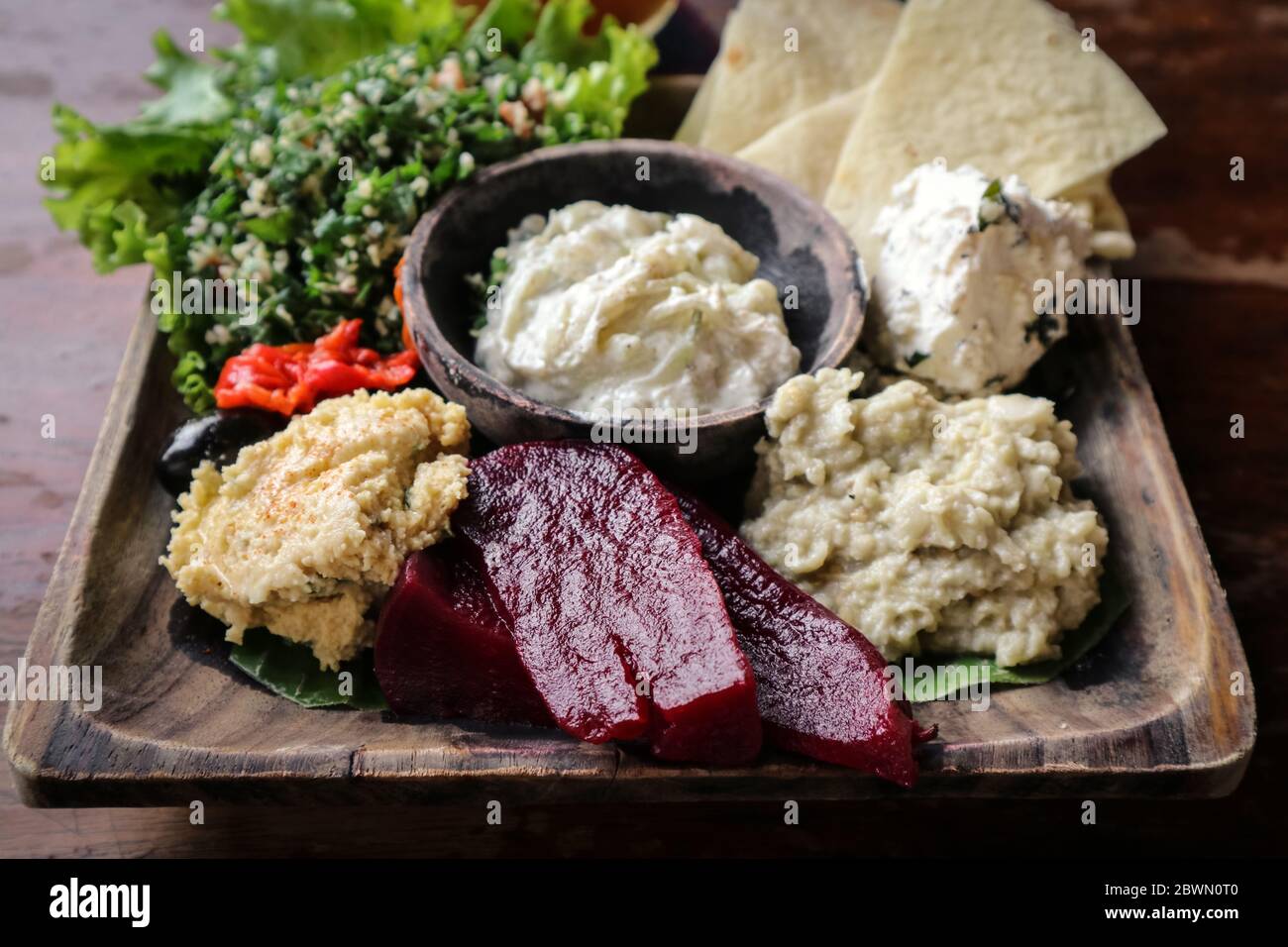 Mezze-Platte mit Hummus, Babaganoush, Tabouli, gerösteten Paprika, Rüben, Feta-Käse und kalamata-Oliven serviert mit Pita-Brot Stockfoto