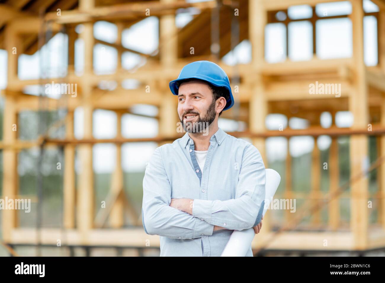 Porträt eines Architekten oder Bauherrn in Harthut vor dem Holzhaus Struktur stehend. Bau und Gestaltung Holzrahmenhaus Konzept Stockfoto