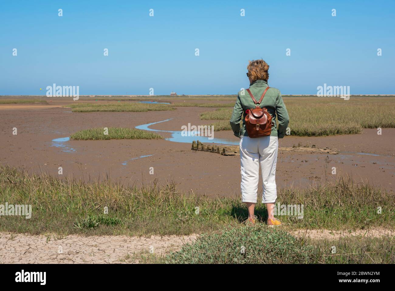 Frau allein denken Konzept, Rückansicht einer reifen Frau Betrachtung einer verlassenen natürlichen Landschaft unter einem blauen Himmel. Stockfoto