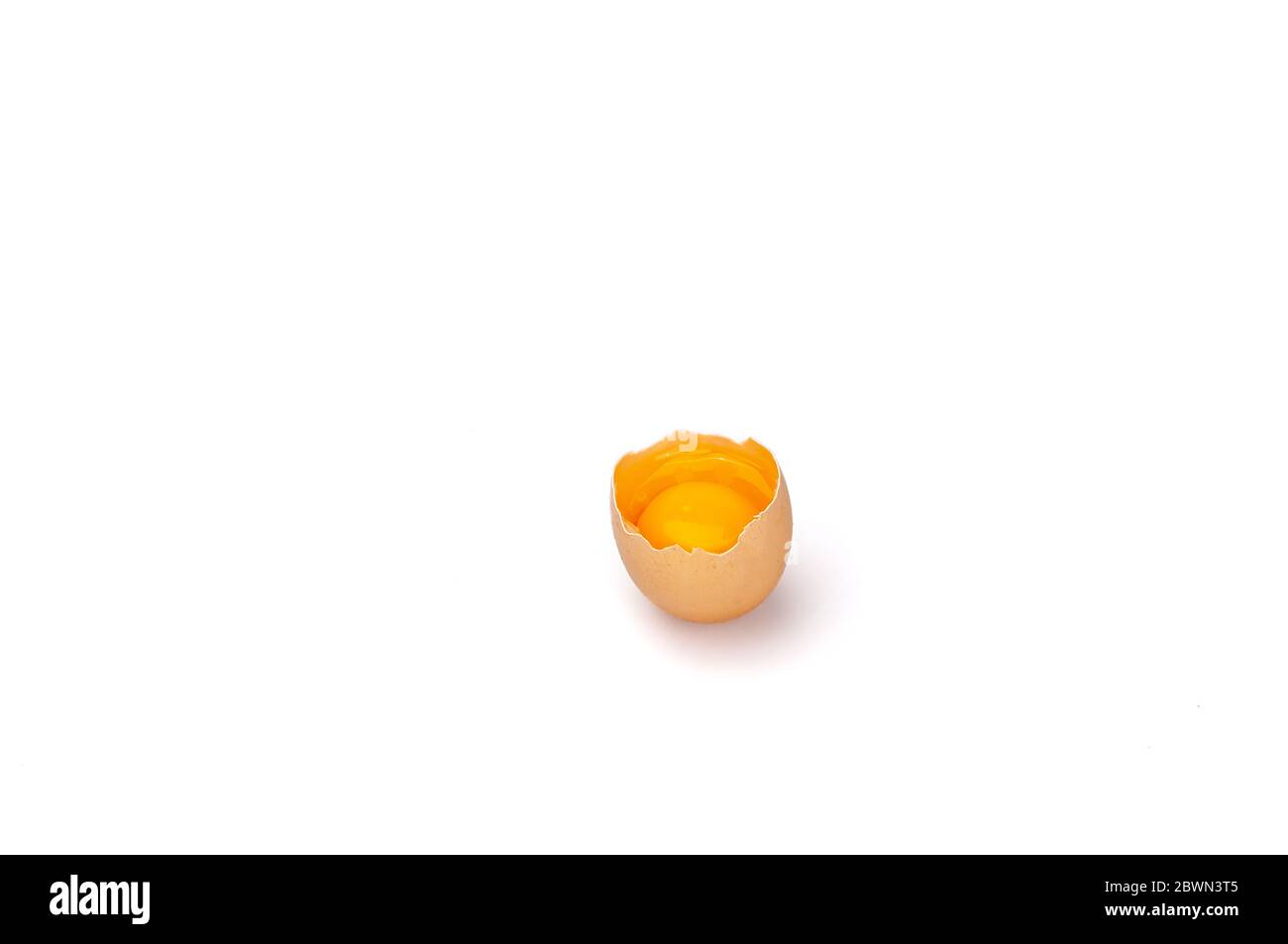 Das rohe Eigelb und die weiße zerbrochene Eierschale. Stockfoto