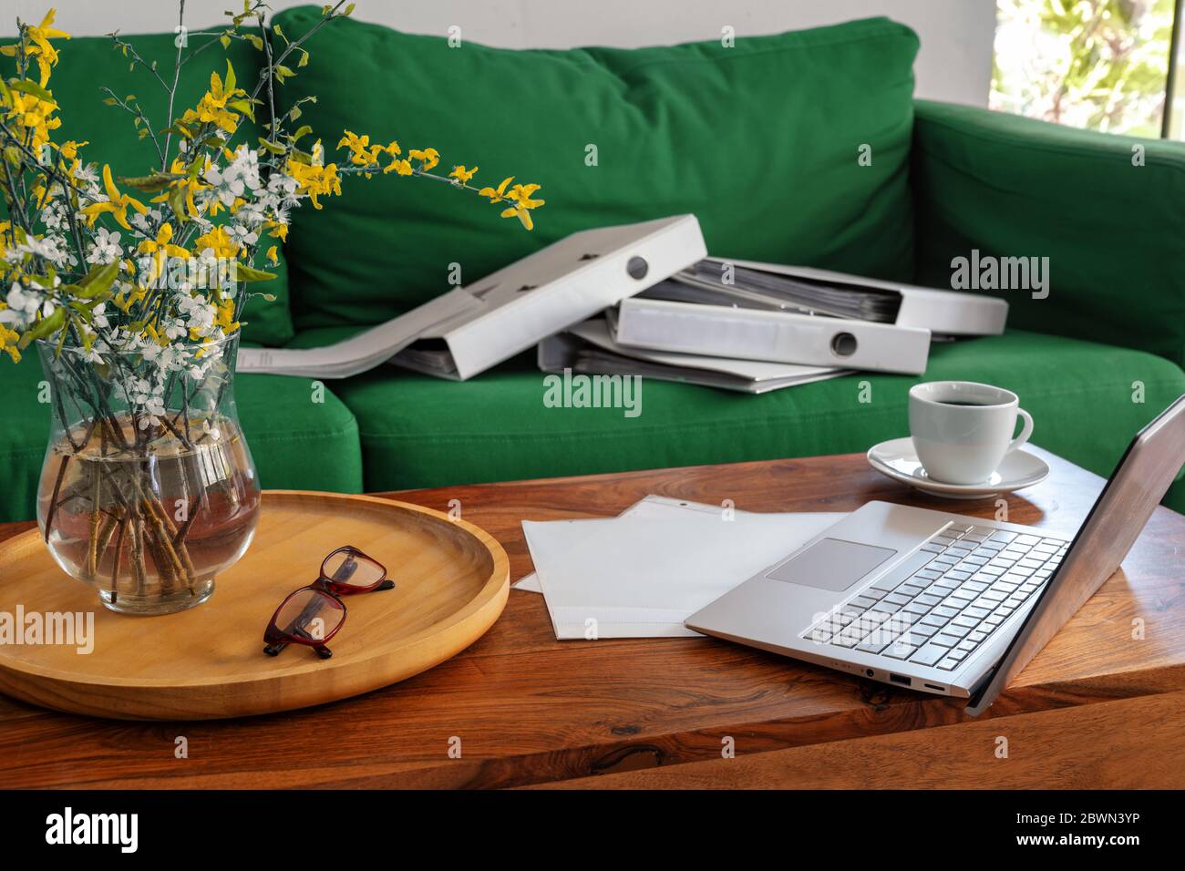 Home Office im Wohnzimmer, Laptop auf dem Couchtisch und Ringordner auf der Couch, außergewöhnliche Arbeitssituation während der Pandemie Coronaviru Stockfoto