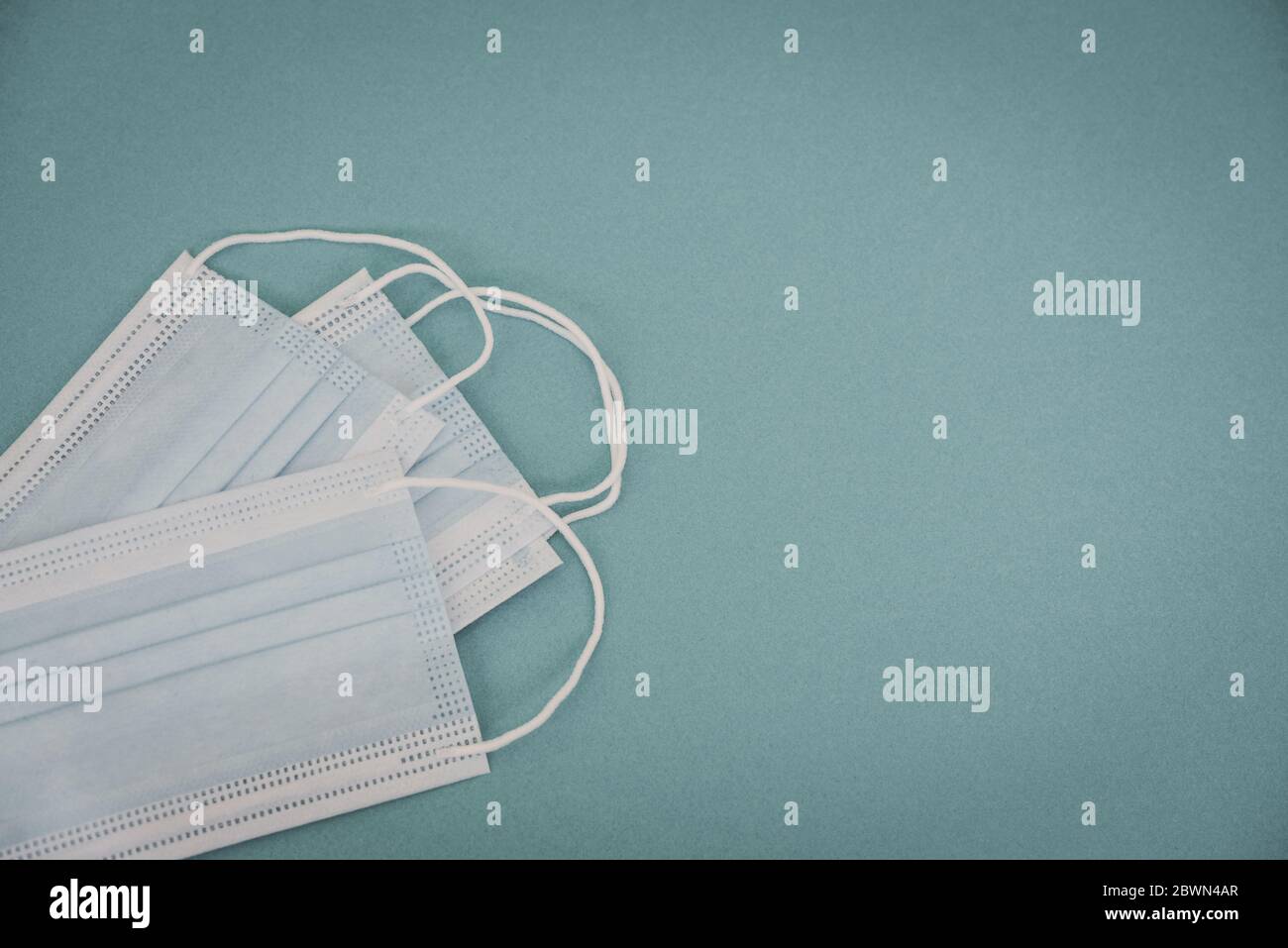 Typische chirurgische Masken mit Gummiohrbändern auf blauem Hintergrund, Draufsicht. Schutzkonzept. Stockfoto