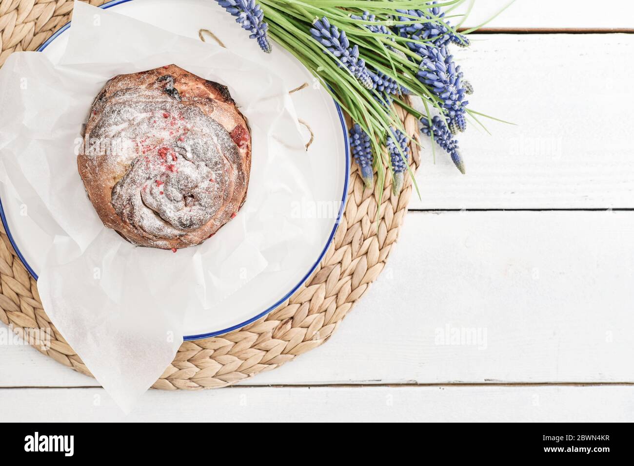 Osterkuchen auf dem Teller und Blumen auf Holzhintergrund Stockfoto