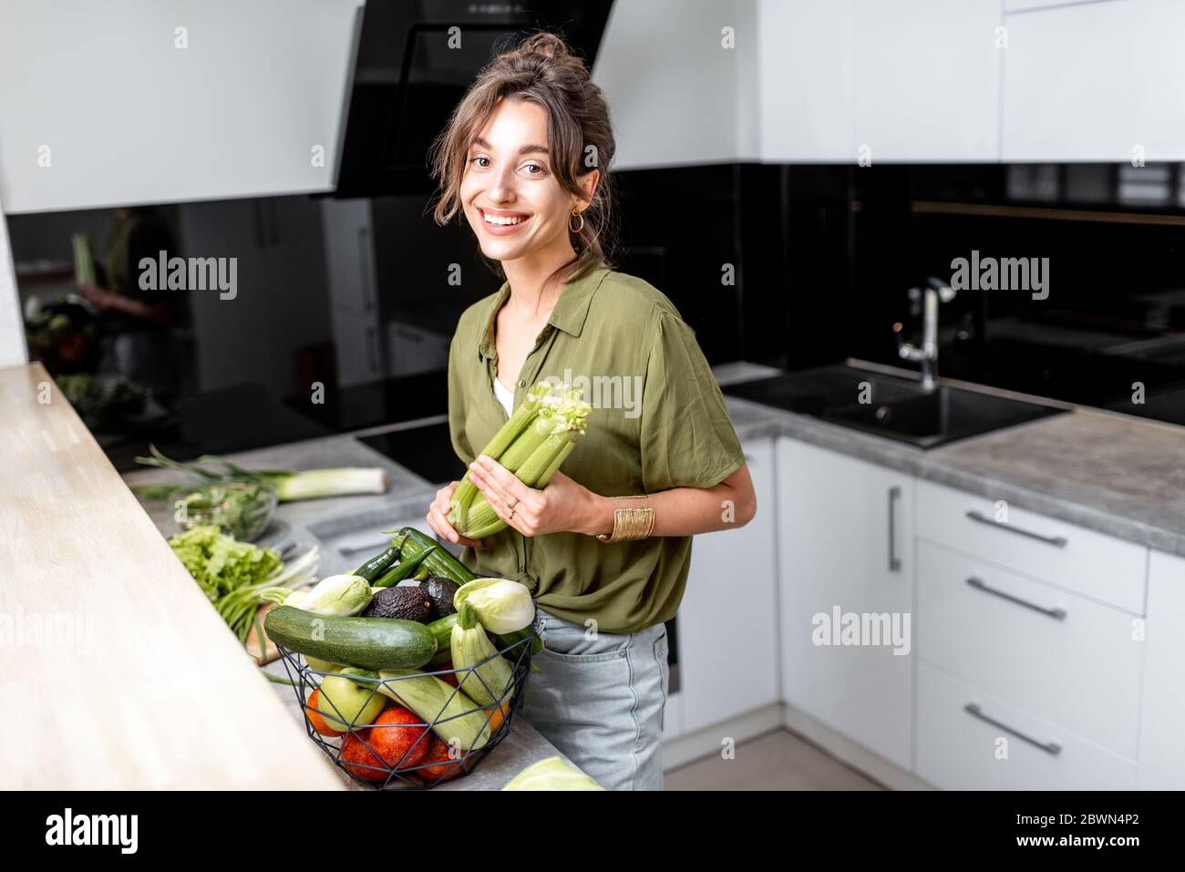 Porträt einer jungen und fröhlichen Frau mit gesundem Rohkost in der Küche zu Hause. Vegetarismus, Wohlbefinden und gesundes Lifestyle-Konzept Stockfoto