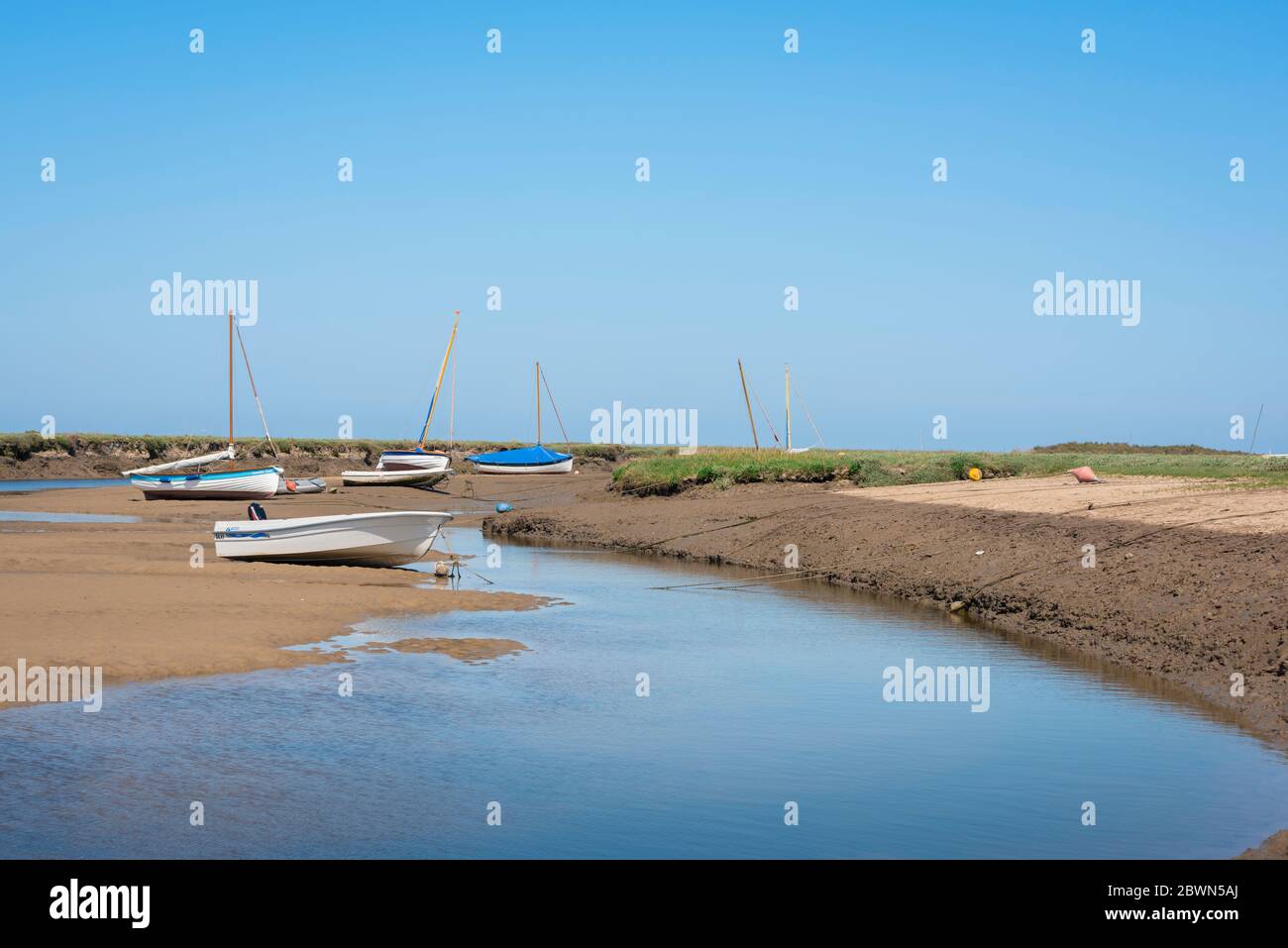 Norfolk Coast UK, Blick im Sommer auf Boote entlang eines Baches in der Nähe des Norfolk Küstendorfes Blakeney, England, Großbritannien. Stockfoto