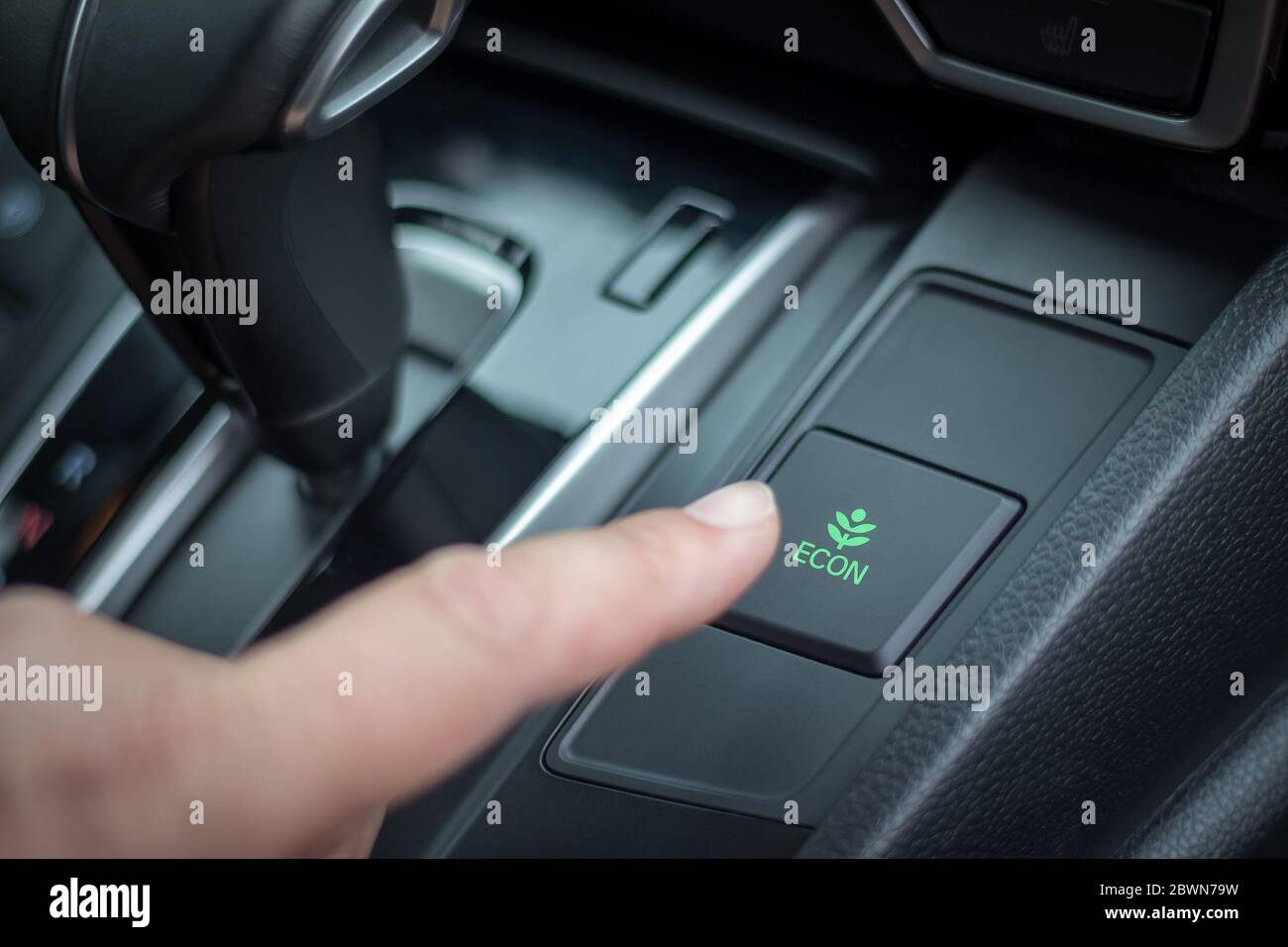 Drücken Sie die Taste econ im Armaturenbrett des Autos mit den Fingern. Reduzierung des Kraftstoffverbrauchs Stockfoto