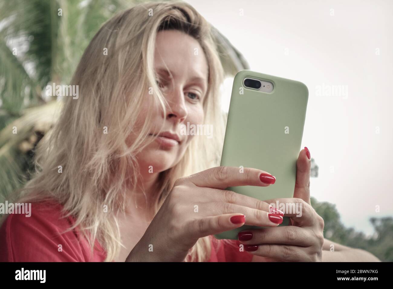 BALI, INDONESIEN - 16. DEZEMBER 2019: Erwachsene blonde Frau, die das iPhone 8 Plus im Freien auf Bali, Indonesien, hält und anschaut. Stockfoto