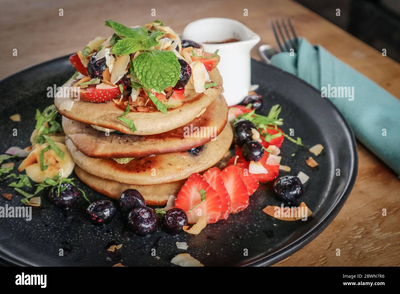 Pfannkuchen mit Banane, Heidelbeeren, Erdbeeren und Schokoladensauce auf einem Teller Nahaufnahme Stockfoto