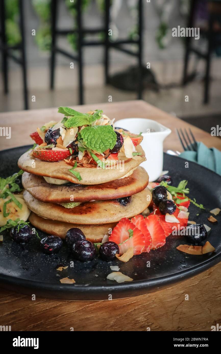 Pfannkuchen mit Banane, Heidelbeeren, Erdbeeren und Schokoladensauce auf einem Teller Nahaufnahme Stockfoto