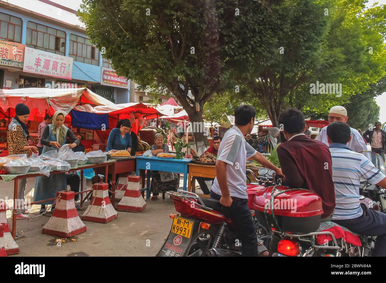 Yining, Xinjiang, China - 13. Juli 2014: Uiguren Frauen verkaufen lokale Produkte auf einem Straßenmarkt in Yining Stockfoto