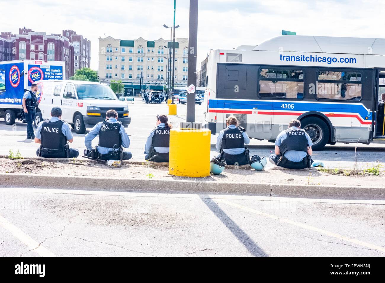 Sehen Sie sich mehrere Polizisten von hinten an, die auf dem Boden in der Nähe eines Einkaufszentrums sitzen.Sie patrouillieren nach den Unruhen in Chicago 2020 gegen Polizeibrutalität. Stockfoto