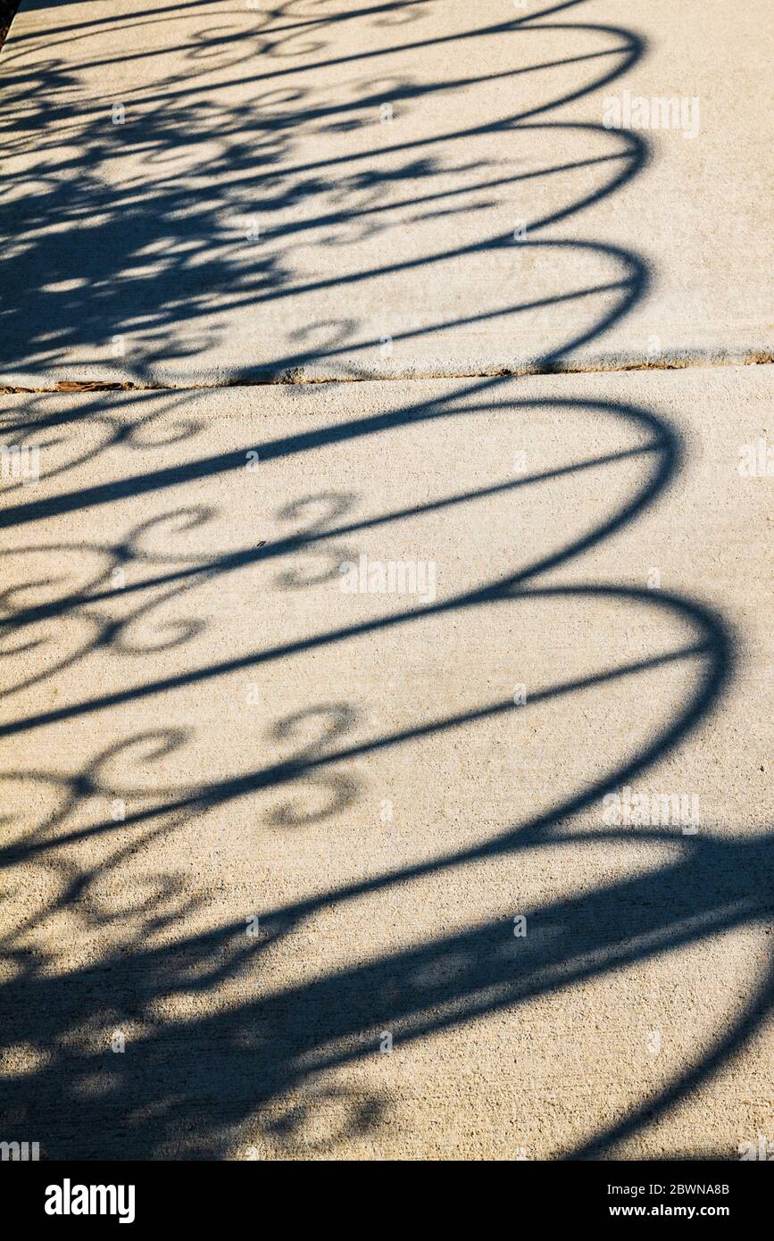 Eisenzaun wirft Schatten auf den Bürgersteig; Heart of the Rockies Regional Medical Center Healing Garden; Salida; Colorado; USA Stockfoto