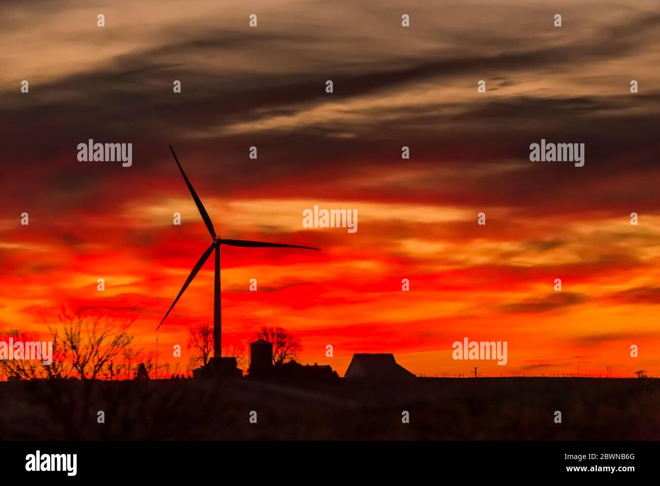 Windmaschine, die Energie gegen einen lebendigen Sonnenaufgang über einer Iowa Farm, USA produziert Stockfoto