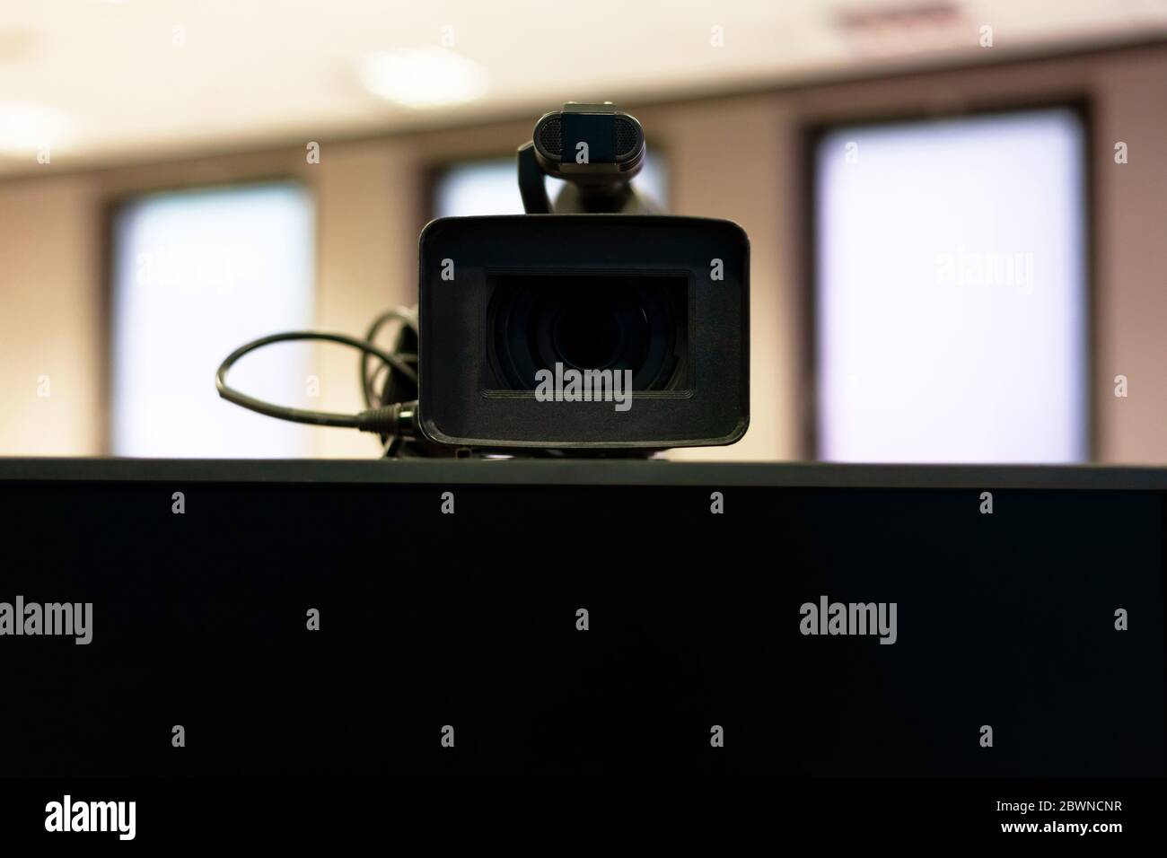 Professionelle moderne Videokamera über einem leeren Bildschirm Nahaufnahme, frontale Aufnahme. Video-Streaming, Vlogging-Karriere oder Telekonferenz Zusammenfassung Stockfoto