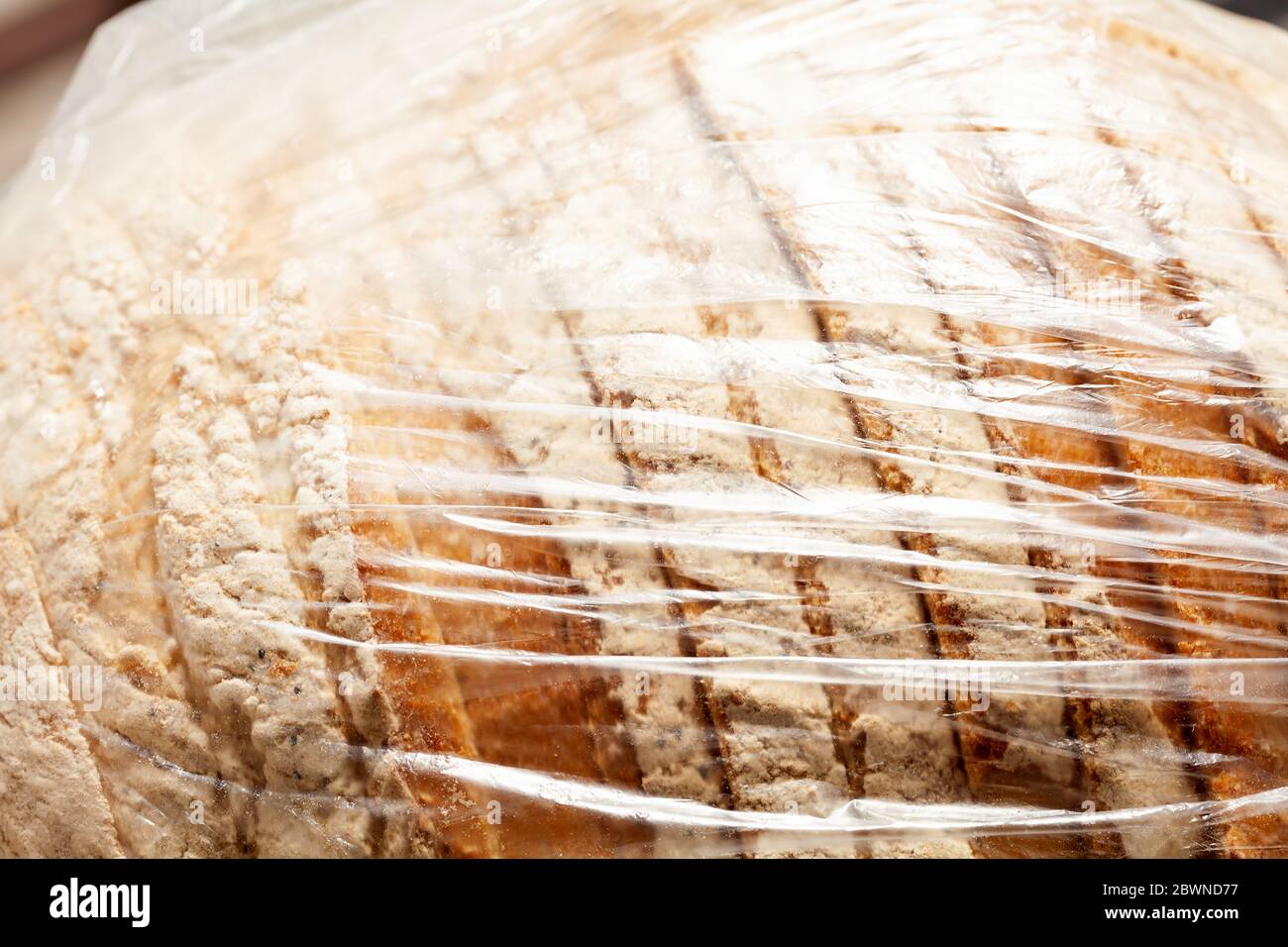 Vorgeschnittenes Brot mit Mehl in einem einfachen durchsichtigen Plastikbeutel Behälter sehen, dicht gewickelt, Makro, Nahaufnahme. Unökologisch nicht umweltfreundlich Stockfoto