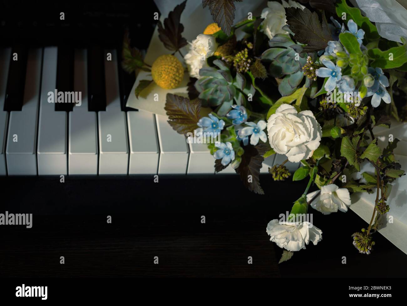 Blumenstrauß auf Klavier in Kontrastlicht gelegt. Romantische Nahaufnahme Stockfoto
