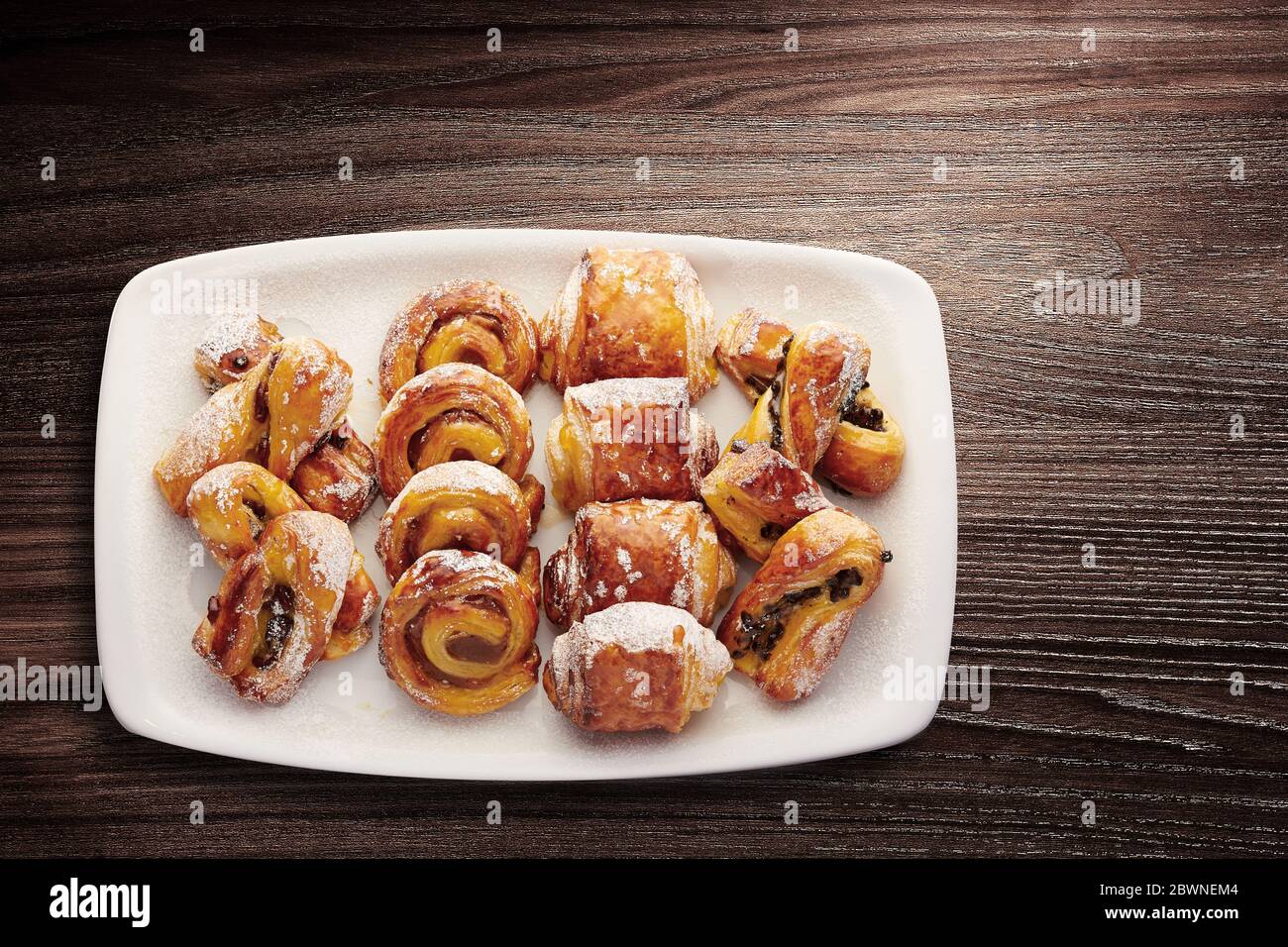 Direkt über dem Schuss gemischtes Frühstücksgebäck, einschließlich Pain au Chocolate und glasierte dänische Gebäckstücke, die auf einem Teller serviert werden Stockfoto