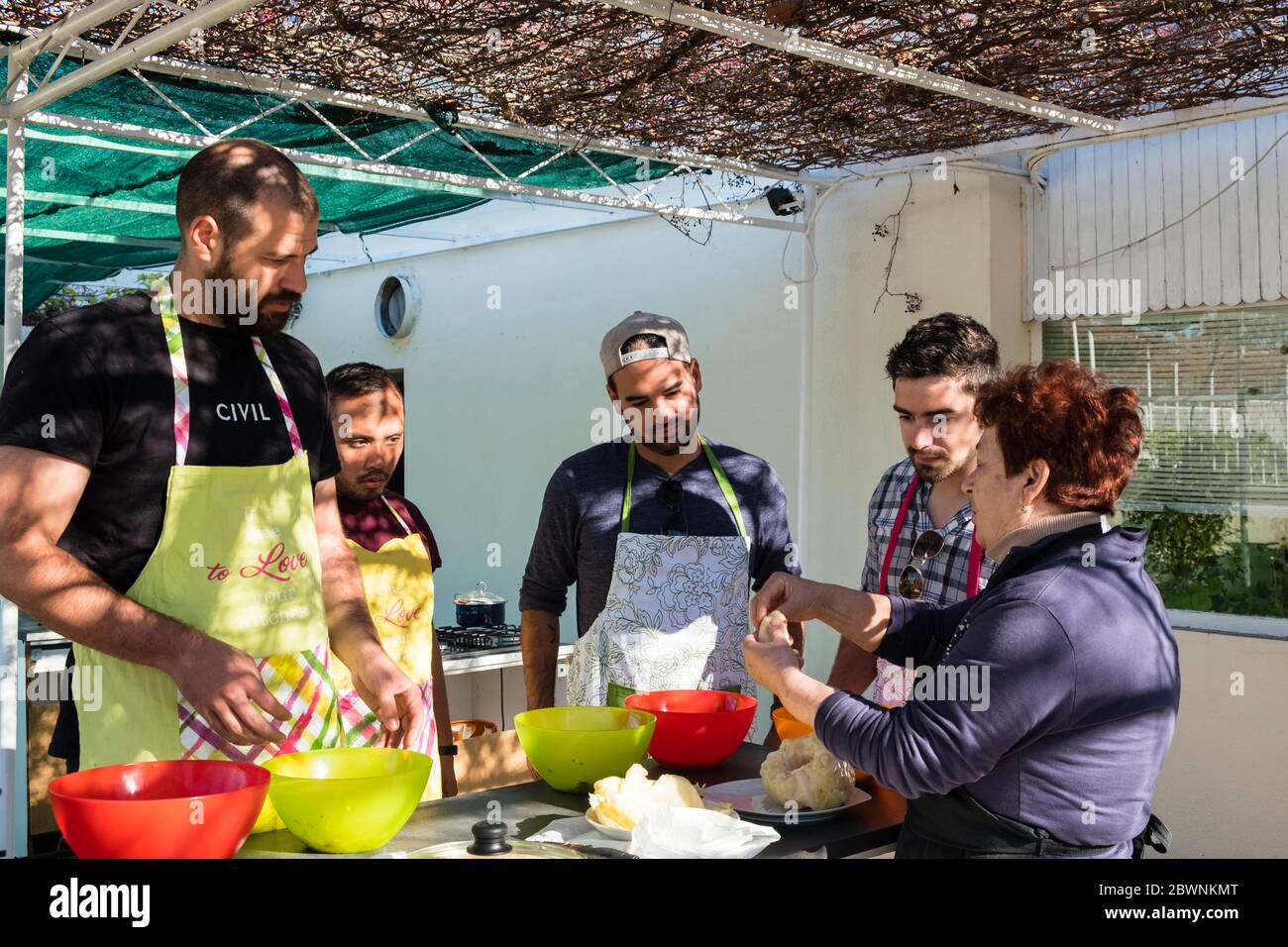 Vier männliche Touristen lernen, wie man dalmatinische Sarma (Kohlbrötchen) bei einem Kochkurs im Freien, dalmatinisches Hinterland, Kroatien, macht Stockfoto