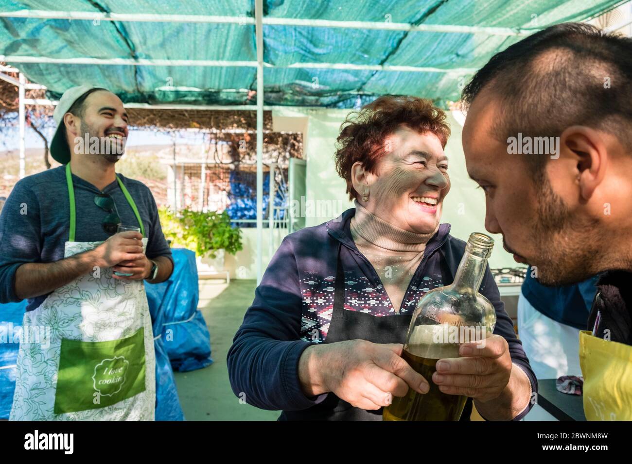 Zwei männliche Touristen lernen von einer Lehrerin bei einem Kochkurs im Freien in den Dalmatinischen Highlands, Dalmatien, Kroatien Stockfoto