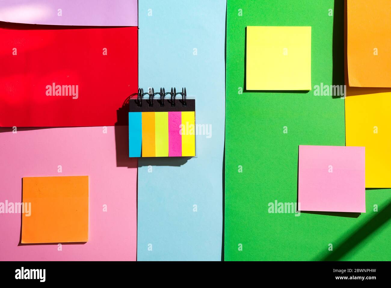 Bunte Haftnotizen auf farbigem Papier Hintergrund mit Kopierraum Stockfoto