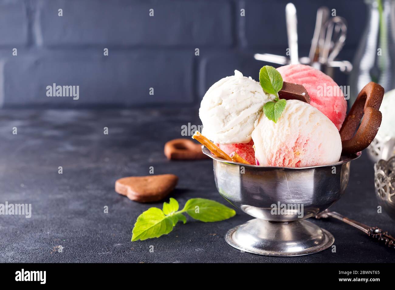 Trio aus leckeren Vanille und Erdbeere aromatisiert gefrorenes Dessert Eis in einer Metallschale mit Minze auf einem Stein Stockfoto