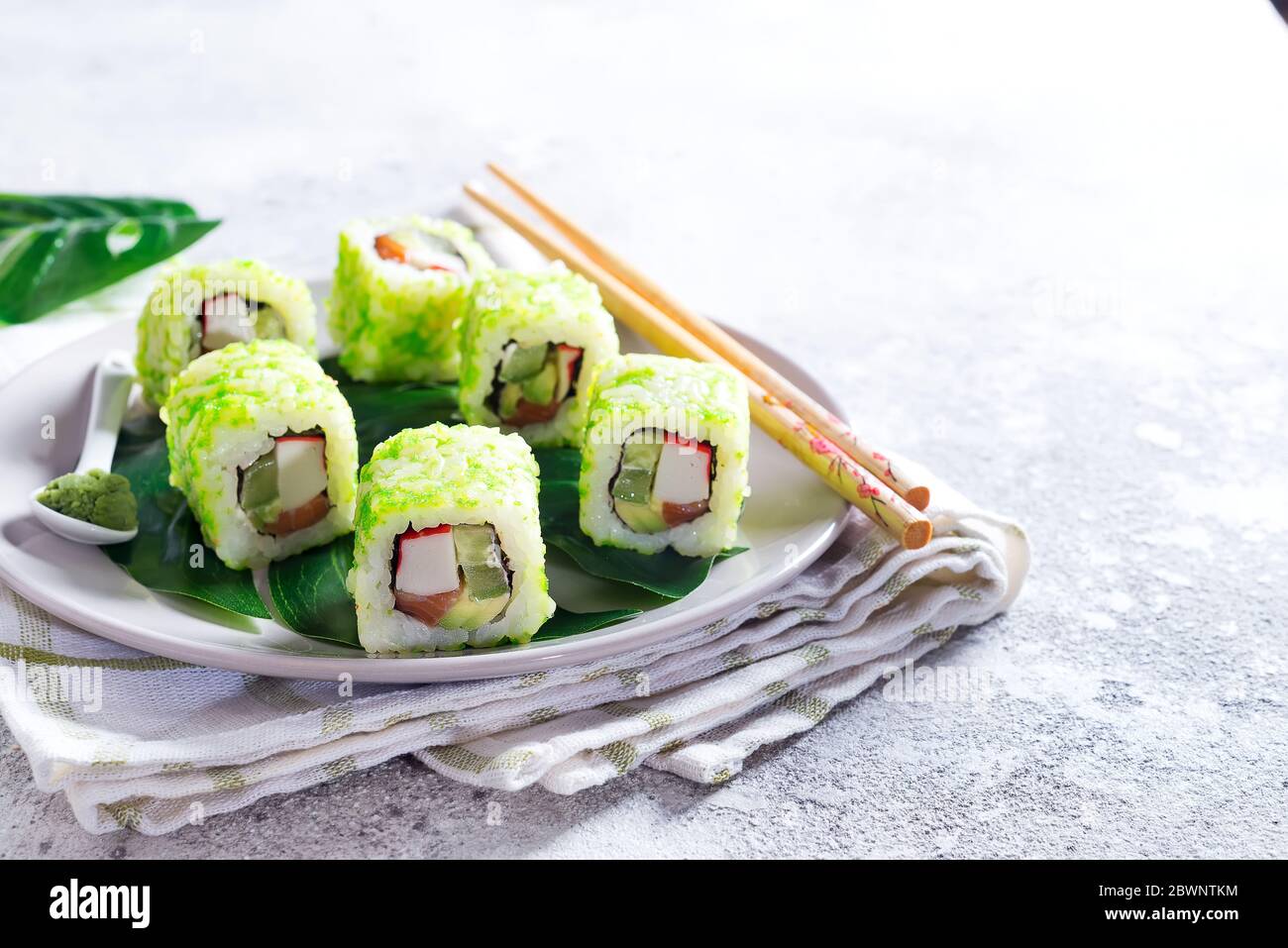 Sushi Rolle mit grünem Kaviar auf einem Teller mit Essstäbchen auf Steingrund. Sushi-Menü. Japanisches Essen Kopierbereich. Stockfoto