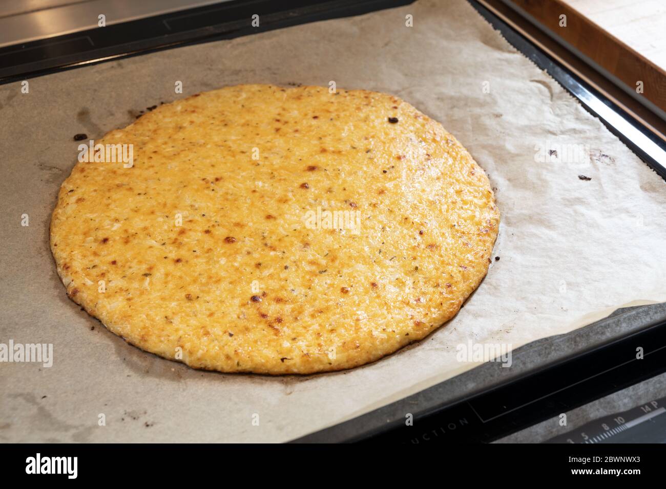 Frisch gebackene Pizzabruste aus geschreddertem Blumenkohl und Käse auf einem Backblech, gesundes Rezept für Schlankheitsmittel mit kohlenarcher oder ketogener Diät, ausgewählt Stockfoto