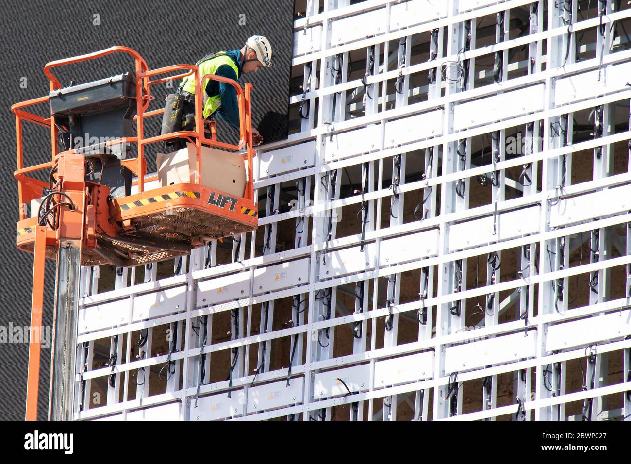 Belgrad, Serbien - 6. Mai 2020: Bauarbeiter im Krankorb installiert Bleche zur Verkleidung der Metallkonstruktion an einer Gebäudefassadenwand Stockfoto