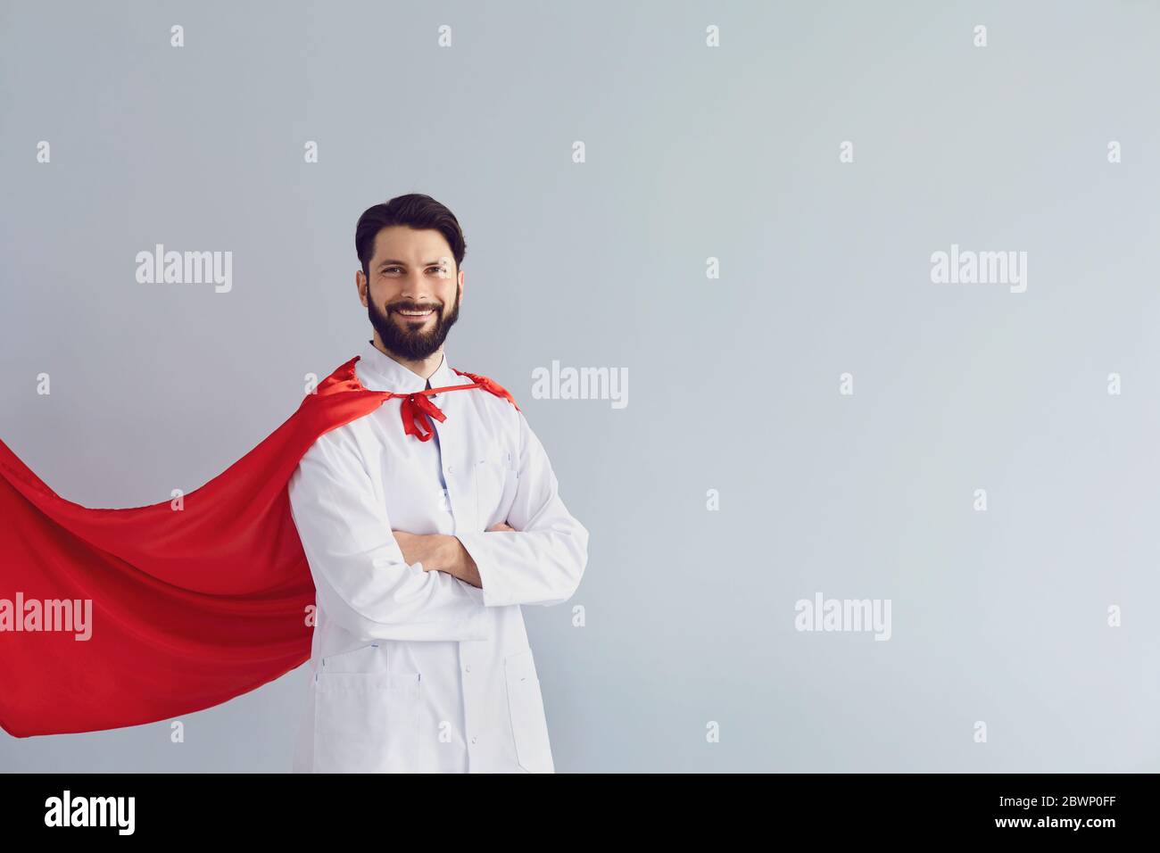 Doktor ist ein Superheld. Arzt im Superhelden Kostüm lächelt auf grauem Hintergrund. Stockfoto
