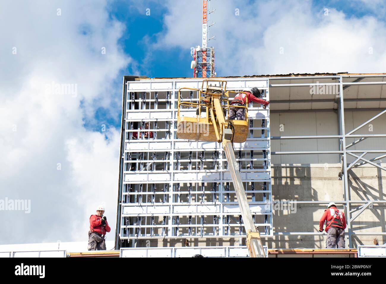 Belgrad, Serbien - 6. Mai 2020: Bauarbeiter auf der Baustelle, die Außenverkleidungen an einer Gebäudefassadenwand mit einem Kran anbauen Stockfoto