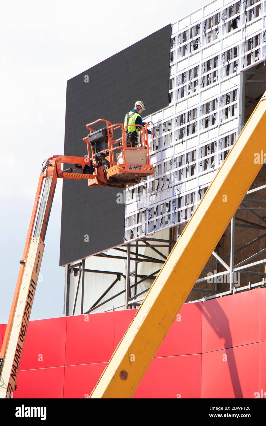 Belgrad, Serbien - 6. Mai 2020: Bauarbeiter im Krankorb installiert Bleche zur Verkleidung der Metallkonstruktion an einer Gebäudefassadenwand Stockfoto