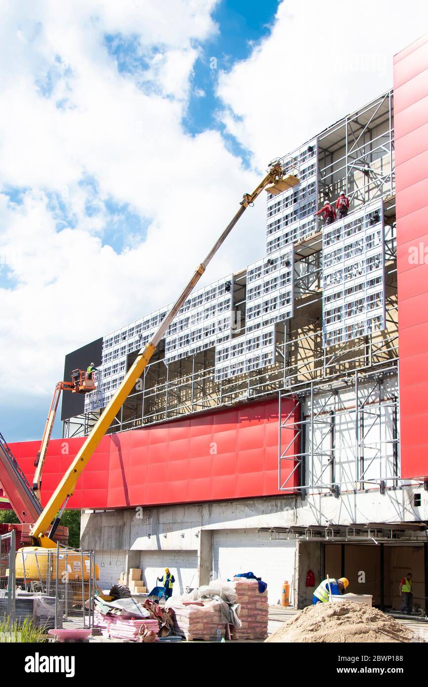 Belgrad, Serbien - 6. Mai 2020: Bauarbeiter auf der Baustelle, die Außenverkleidungen an einer Gebäudefassadenwand mit Kranen anbauen Stockfoto