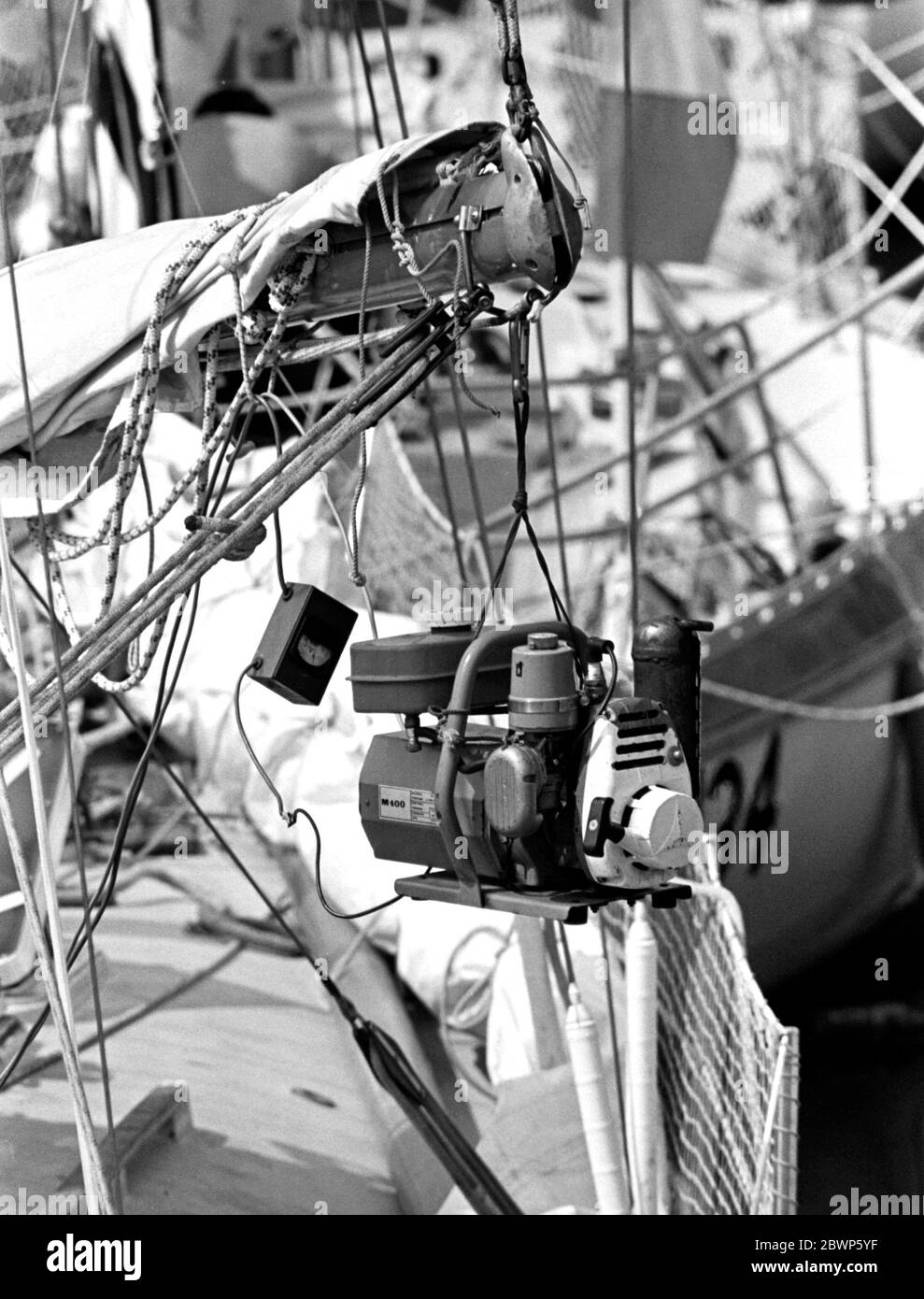 AJAXNETPHOTO. 1976. PLYMOUTH, ENGLAND. - OSTAR 1976 - TRAGBARER ELEKTRISCHER GENERATOR HING AN EINEM GROSSSEGELBOOM DER KONKURRENZ, UM VIBRATIONEN IN MILBAY DOCKS VOR RENNBEGINN ZU DÄMPFEN. FOTO: JONATHAN EASTLAND/AJAX REF:2760506 19A Stockfoto