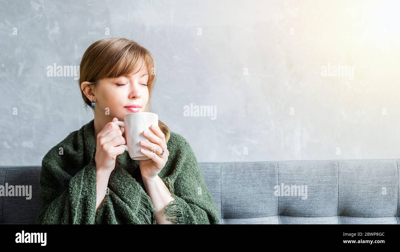 Fröhliches Mädchen zu Hause hält eine Tasse, genießen inhaliert das Aroma des Drink.Homeliness, glückliches Zuhause bleiben und Kaffee am Morgen Konzept Stockfoto