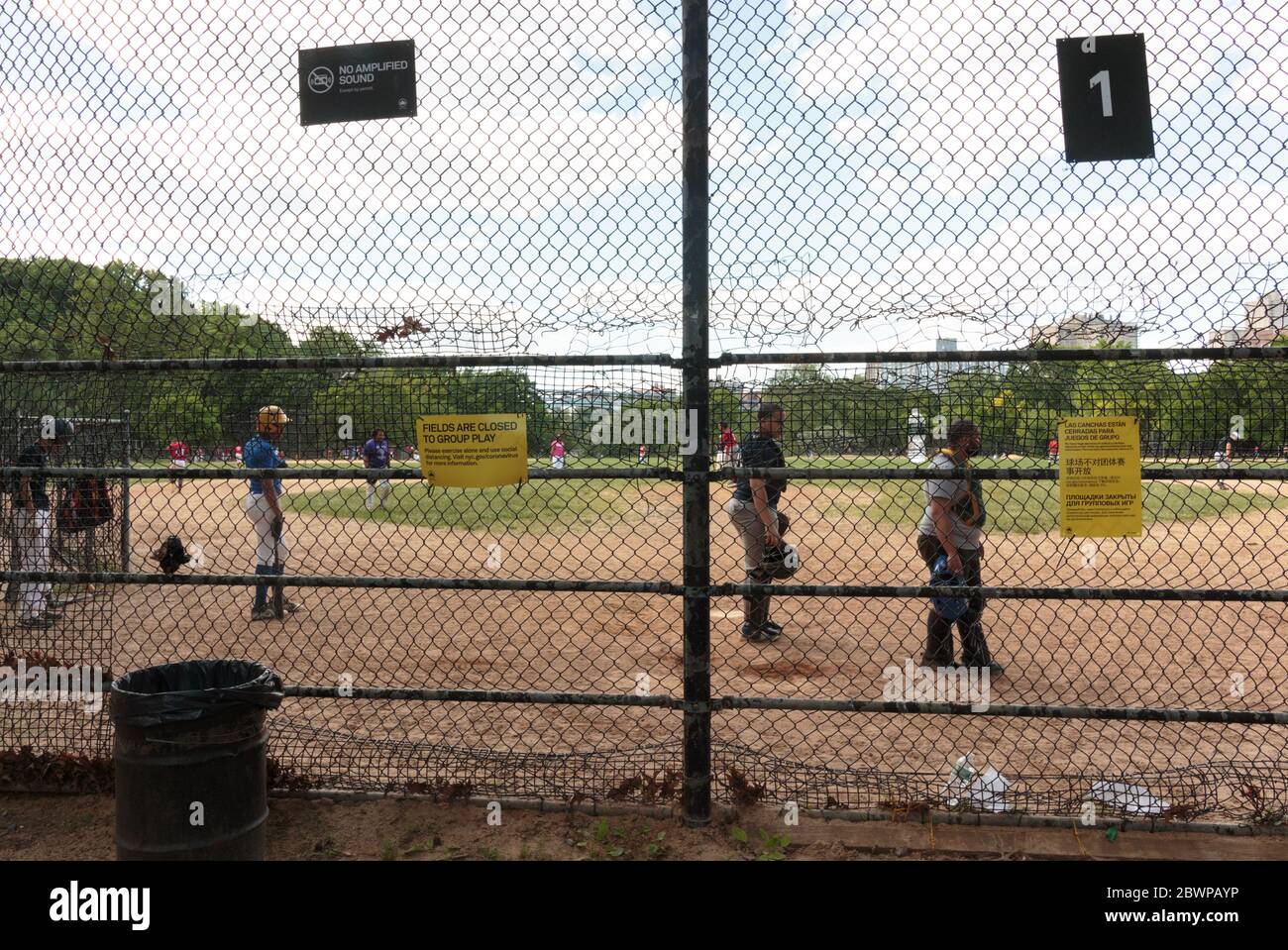 Leute, die ein Baseballspiel im Inwood Hill Park an einem Sonntag spielen, obwohl Gruppenspiele wegen der coronavirusor Covid-19 Pandemie verboten sind Stockfoto