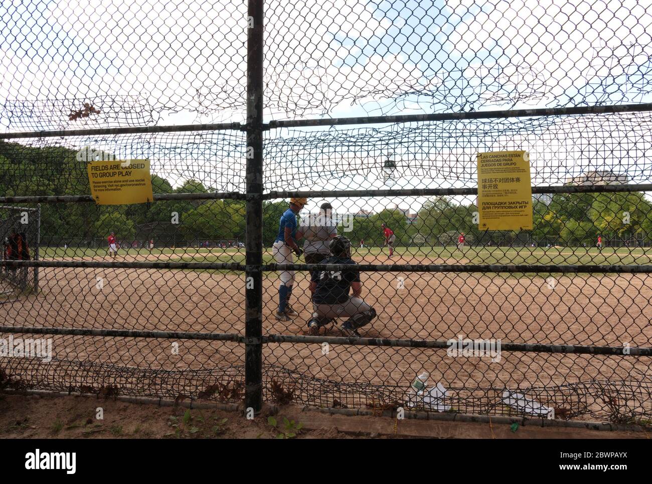 Leute, die ein Baseballspiel im Inwood Hill Park an einem Sonntag spielen, obwohl Gruppenspiele wegen der coronavirusor Covid-19 Pandemie verboten sind Stockfoto