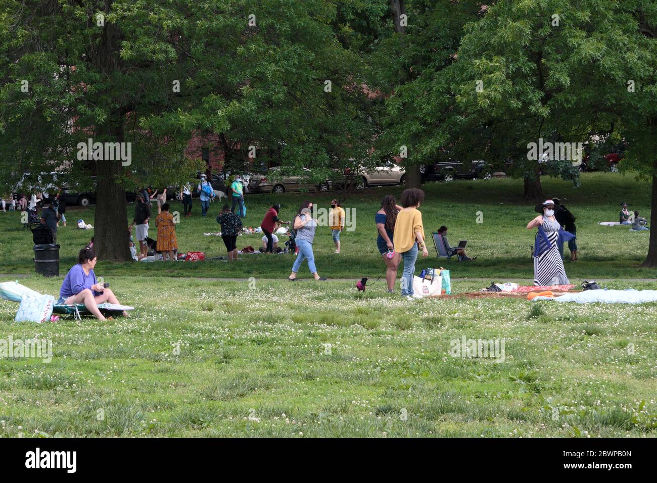 Leute, die sich im Inwood Hill Park entspannen, einige mit Masken, andere ohne, am Wochenende Stockfoto