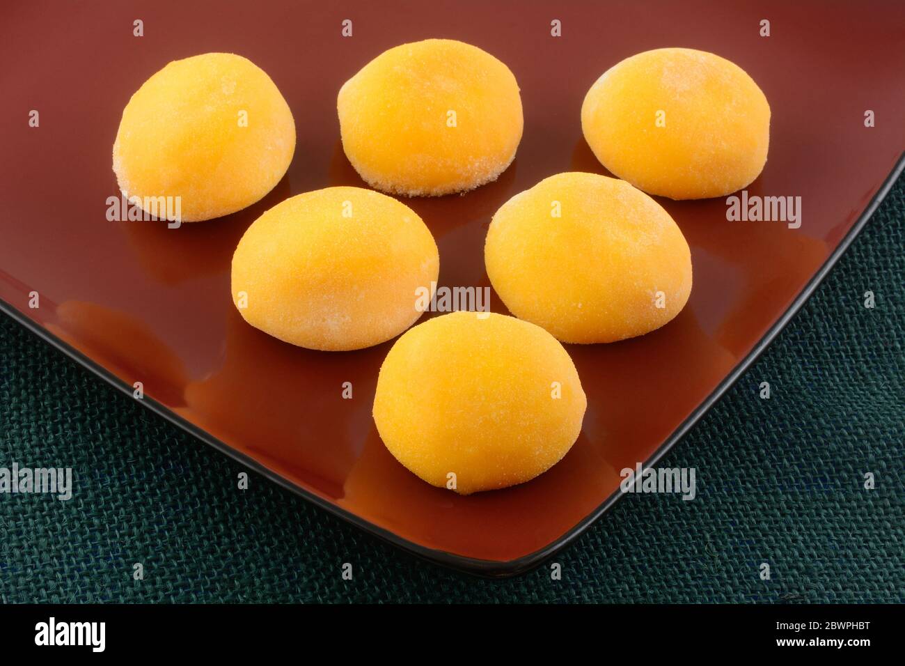 Nahaufnahme von Mango-Eis-Mochi-Kugeln auf roter Servierplatte Stockfoto