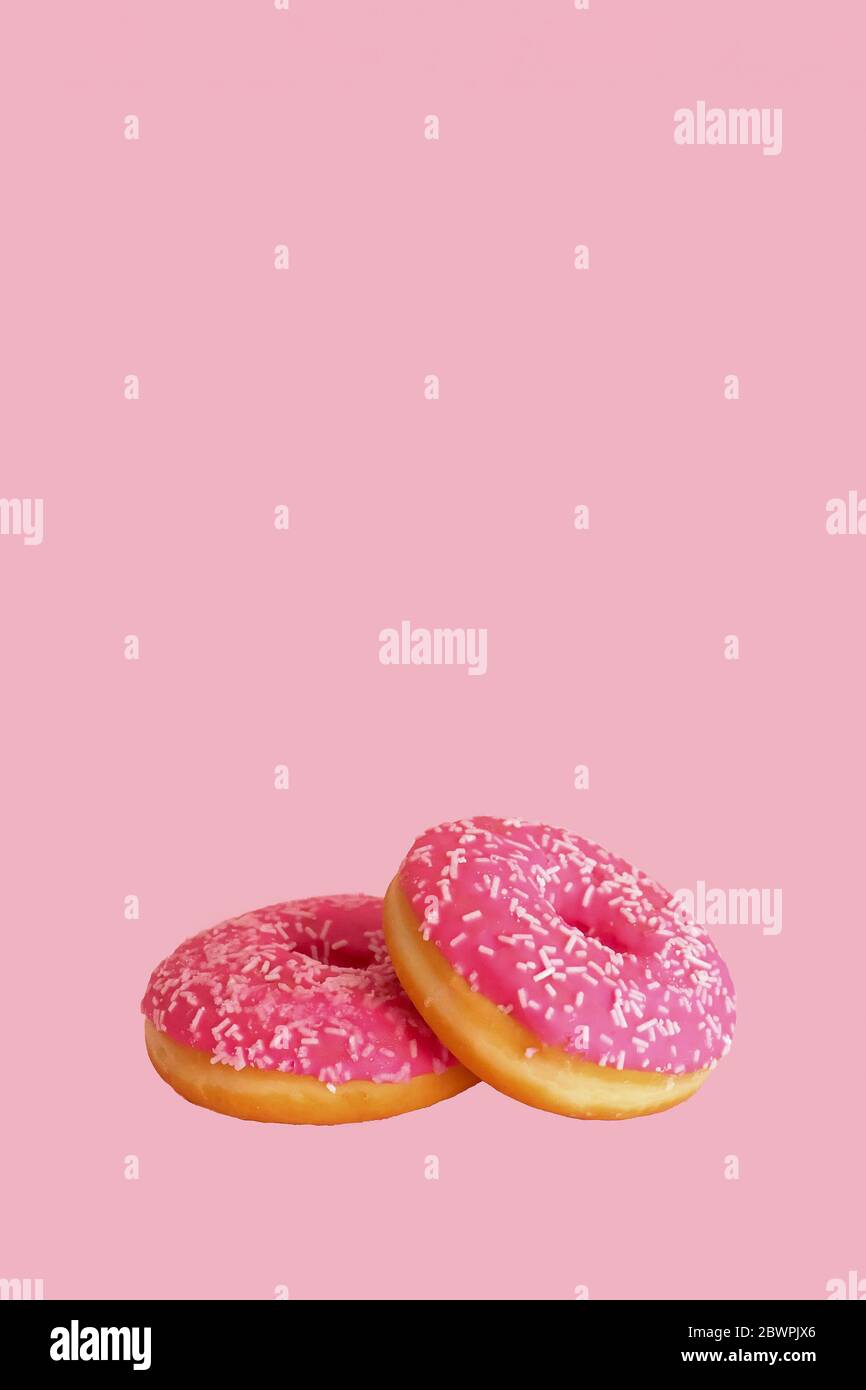 Zwei rosa glasierte Donuts auf rosa Hintergrund. Kopierbereich. Konzept des Donut-Tages. Nationalfeiertag Donut. Gebäck. Hintergrund, Poster oder Banner für Bäckerei. Stockfoto