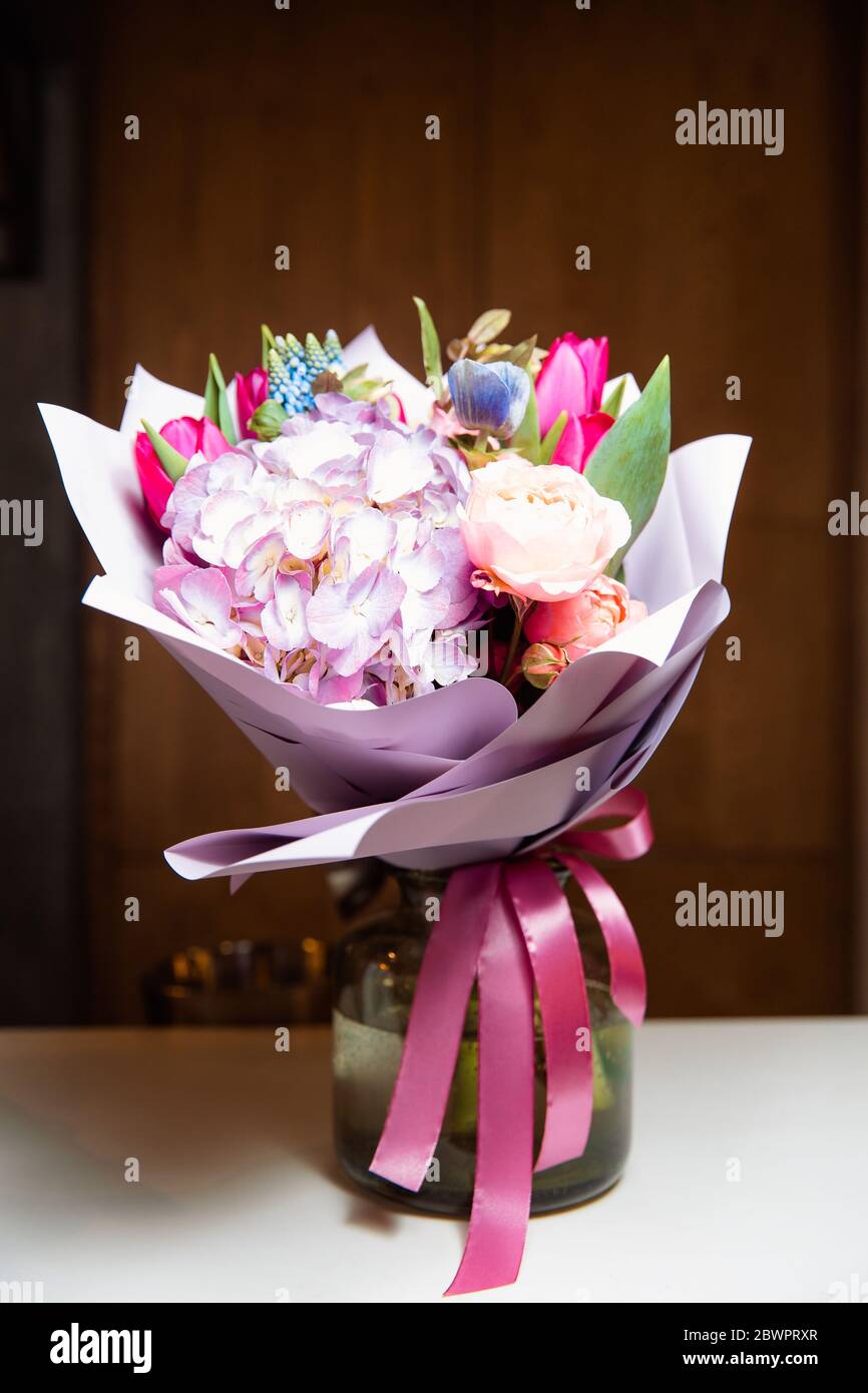 Ein großer Strauß von bunten Blumen verschiedener Art steht in einer transparenten Glasvase. Stockfoto