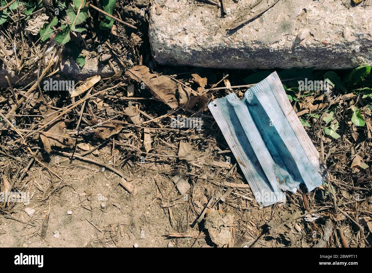 Eine gebrauchte medizinische Gesichtsmaske, die während der Covid-19-Pandemie auf den Boden geworfen wurde. Konzept der Umweltverschmutzung Stockfoto
