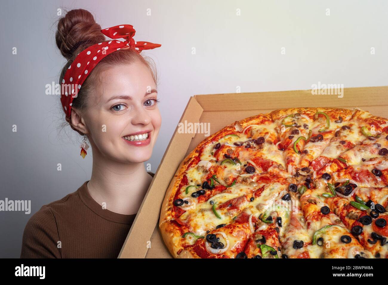 Lächelnde junge kaukasische Frau Mädchen hält eine große Familie Größe ganze Pizza. Konzept für die Lieferung von Lebensmitteln Stockfoto