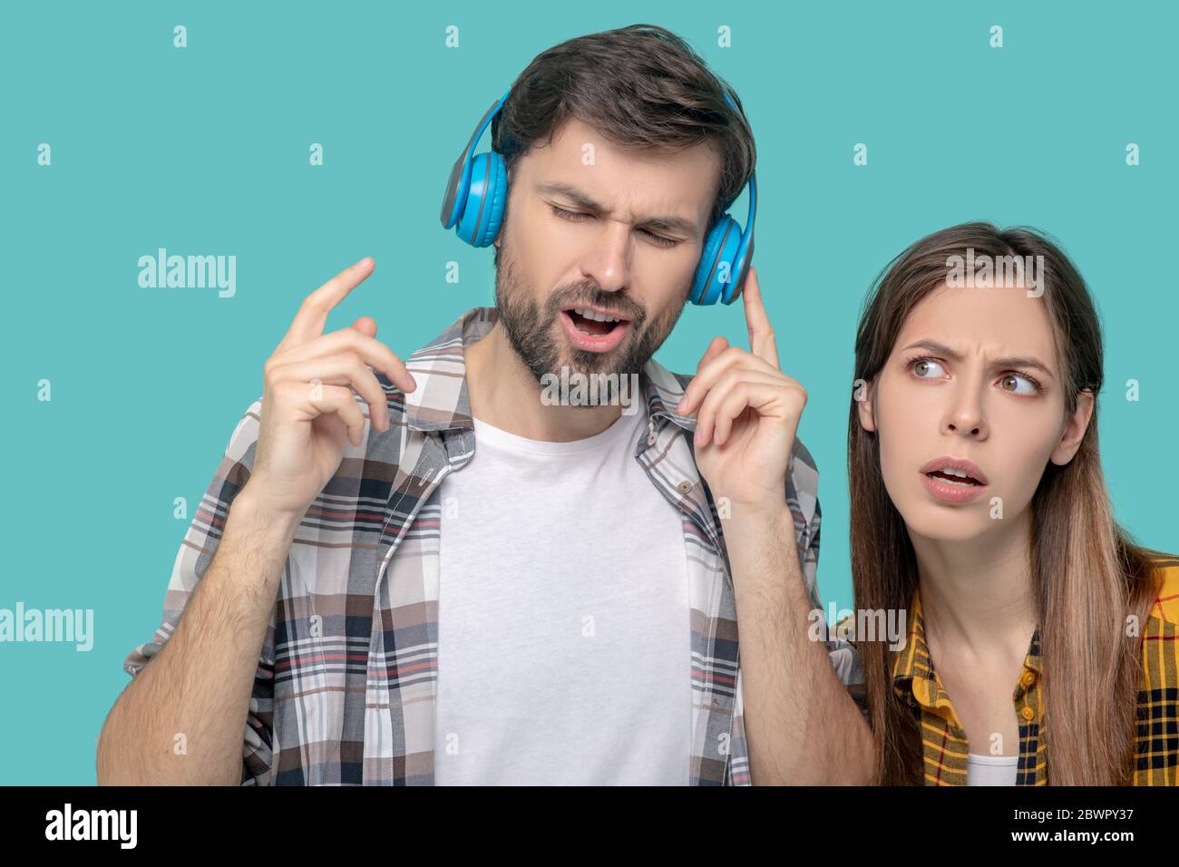 Mann in Kopfhörer mit geschlossenen Augen und ein ernsthaftes Mädchen Stockfoto
